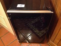 Front view of black Magic Chef wine cooler with reflective glass door, closed.