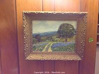 Single oil painting of countryside field of bluebonnets with distant hills, in ornate carved wood frame