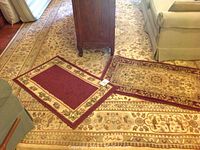 Large beige floral patterned area rug under furniture with two small mats laid on top