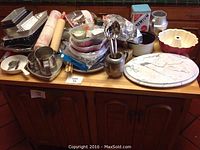 Full lot view showing all items on a wooden cabinet top including bakeware, marble turntable, bowls, and cracker tin.