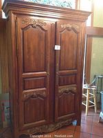 Front view of large Hickory wood armoire with two paneled doors and carved detailing