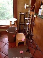 Photo showing the collection including the copy stand, plant stands, stools, desk lamp, and trash bin arranged on tile floor near a window and wood-paneled wall.