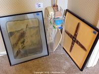 The lot's three main items arranged on the floor against a wall: framed artwork, acrylic telephone stand with beige telephone, and framed boomerang.