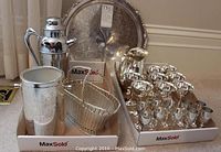 Wide view of all items in the set displayed together: tray in background, cocktail shaker, pitcher, basket, glasses, and ice bucket visible