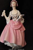 Front view of Royal Doulton Ballad Seller figurine showing pink gown and bonnet, holding scrolls.