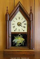 Full front view of Seth Thomas wooden double steeple shelf clock with painted floral glass panel door and Roman numeral dial.