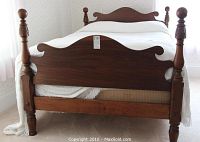 Front view of the entire 4-poster bed showing the carved posts and shaped headboard and footboard.
