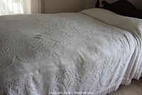 Full view of double size white candlewick bedspread on bed with floral pattern and fringe edges