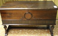 Front view of cedar chest showing carved circular medallion and scroll accents, missing keyhole key
