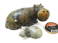 Front view of mother and calf sculptures next to Kiwi shoe polish tin