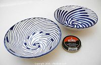 Two blue swirl porcelain bowls side by side with a small container of shoe polish for size reference, showing the interior swirl pattern.