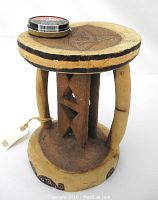 Side view of the Batonka elder's stool showing three curved legs and circular base with painted designs.