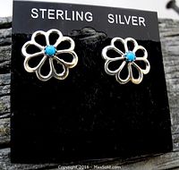 Close-up photo of Navajo sterling silver sunflower earrings with turquoise inlay on black display card labeled 'STERLING SILVER'.