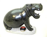 Front-right-side view of dark green hippo sculpture with open mouth, Kiwi shoe polish tin for scale