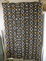 Photo of Bogolanfini mud cloth hanging vertically, showing full geometric pattern in black, white and brown.