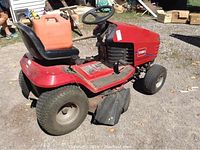 Side view of red Toro Wheel Horse riding mower with black seat and orange gas can on seat