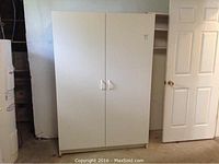 Front view of white two-door storage cabinet with handles, closed doors.