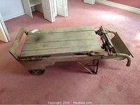 Side view of entire platform scale showing wooden deck, handle and wheels