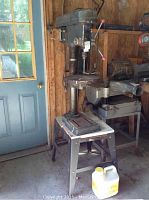 Full view of Westward drill press mounted on metal table in workshop setting near door.