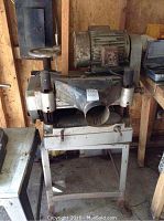 Front and side view showing planer body, motor, dust outlet, and metal base.