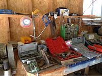 Overall view of workbench with various tool cases, saws, and battery charger