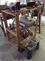 Wooden pine shelving unit with various items including POSCO cash register and small hand tools on shelves.
