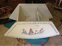 White child's rocking chair with hand-painted rabbit and floral motif on the seatback, showing some wear and paint chipping.