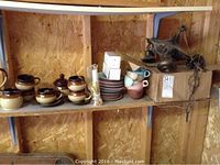 Shelf with pottery tea set including cups, saucers, sugar bowl and teapot, alongside miscellaneous items including an early hanging light