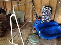 Hockey net, sleds, weights, sticks, fishing net, and swimming boards arranged in a wooden shed corner