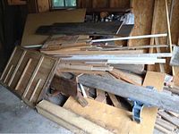 Large pile of mixed wood pieces stacked in a shed or garage space.