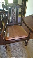 Full view of vintage wooden arm chair showing carved back, upholstered seat and twisted spindle arm supports and legs