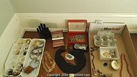 Photo showing assortment of costume jewelry including black beaded necklace, multiple chains, earrings in trays, and an Orbit wristwatch.