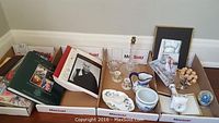 Wide shot of all items including books, bone china vase, plate, candle holders, picture frames, flower arrangement, and snow globe.