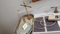 Photo of decorative metal tray with intricate border and rotating gold-tone earring stand holding small jewelry items.
