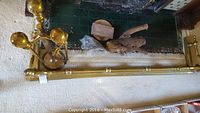 Wide shot showing the brass fireplace fender on carpeted floor with fireplace tools in background.