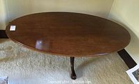 Full view of large oval mahogany coffee table shows polished wood surface and sturdy pedestal leg.