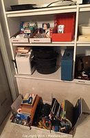 Shelf with assorted office supplies and black roasting pans stacked