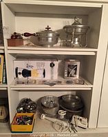 Shelf with 12" chafing dish with wooden handle, blender in original box, small boxed item and various metal pans and utensils below.