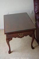 Full top-down view showing the mahogany table with glass top beside a maroon chair on a carpet.