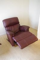 Front angle view of the brown faux leather recliner with footrest extended, showing cushioned seating and padded armrests.