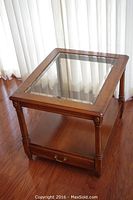 Full view of the wooden rectangular end table with beveled glass top showing legs and bottom shelf with drawer underneath.