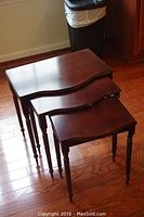 Trio of nesting tables stacked together showing size differences and smooth wood finish