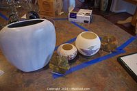 Photo showing three souvenir bud vases of different sizes and designs, along with two mineral specimens on a countertop