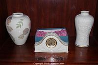 Three Lenox porcelain items displayed on wood shelf: two vases and a gold-trimmed clock in blue box with key