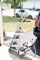 Two-step ladder with close-up of the larger, three-step ladder setup outdoors in daylight.