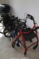 Photo showing one wheelchair and two walkers, all lined up along a wall.