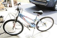 Side angle of the blue Huffy Tundra bike showing front suspension fork, tires and frame condition.