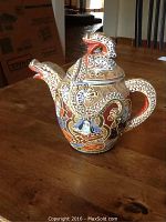 Full view of the teapot showing dragon spout, handle, and lid with multicolor textured porcelain artwork.