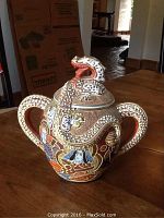 Full view of the sugar bowl showing dragon lid, two handles, and raised dragon and face decorations