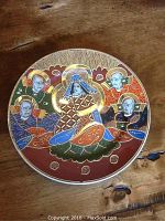 Close-up front view of a single Japanese porcelain plate showing the central figure in traditional attire surrounded by four attendants with gold and colorful detailing.